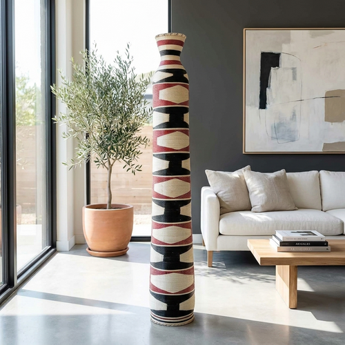 Tall column basket with a black, red and cream pattern standing in a bright living room