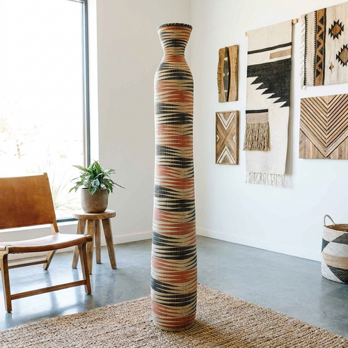 Tall column basket with orange and black striped patterns in a bright room with textiles