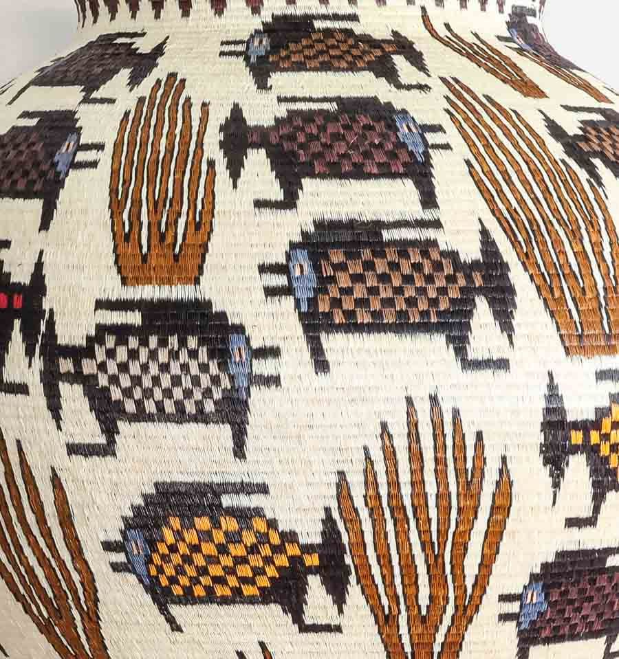Close-up detail of dotted fish motif and coral geometric weaving pattern in Wounaan palm fiber basket