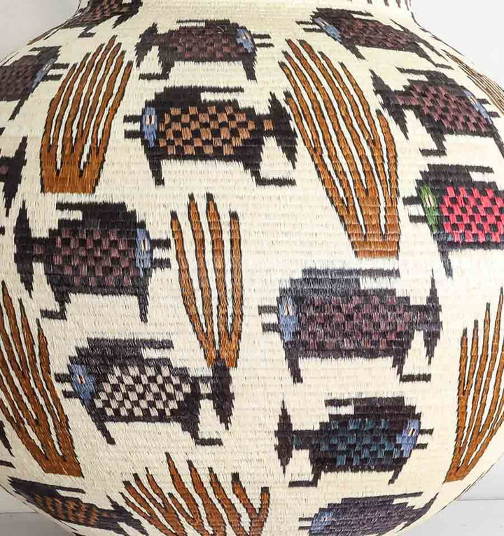 Close-up detail of dotted fish motif and coral geometric weaving pattern in Wounaan palm fiber basket