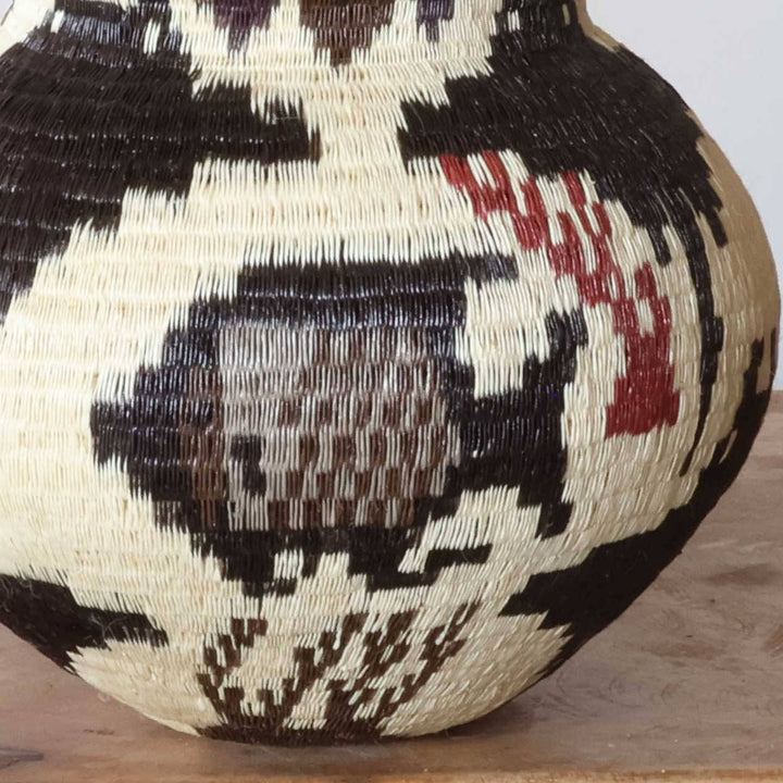 Close-up detail of intricate fish motif and coral lattice weaving in natural palm fiber basket