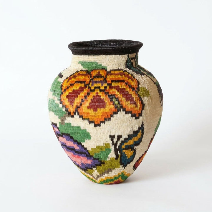 Back view of handwoven Wounaan basket showing rust and marigold winged motif and purple leaf on cream weave