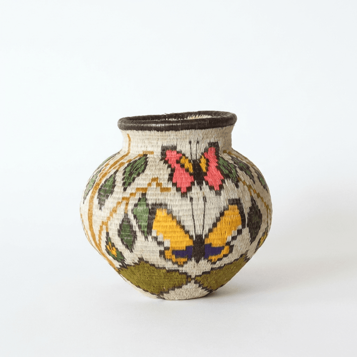 Wounaan basket front view with rose butterfly above golden butterfly edged in black, olive leaves on cream