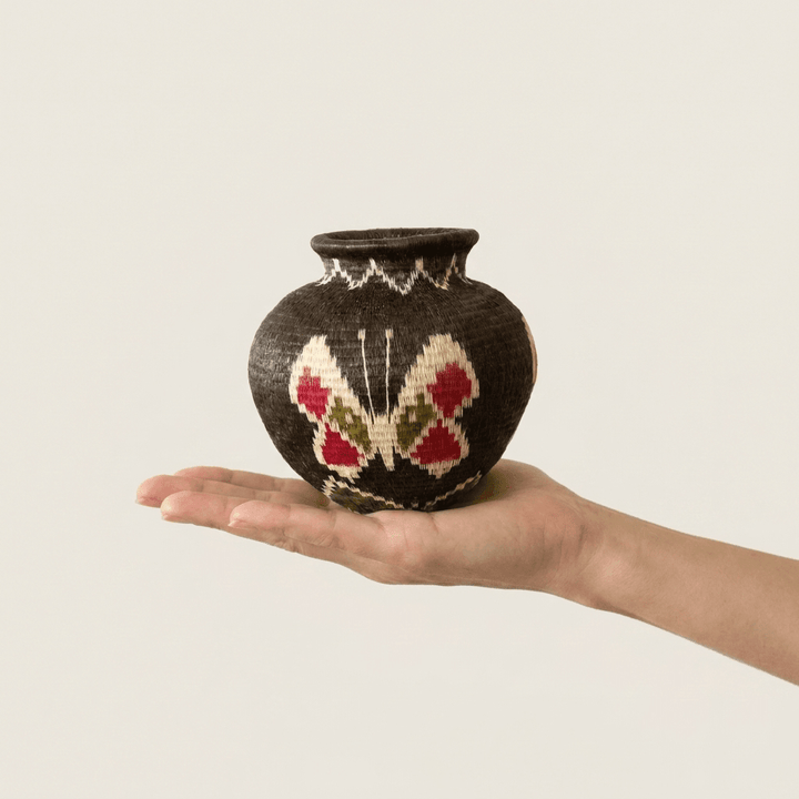 Cacao-brown handwoven Wounaan butterfly basket held in hand showing miniature scale
