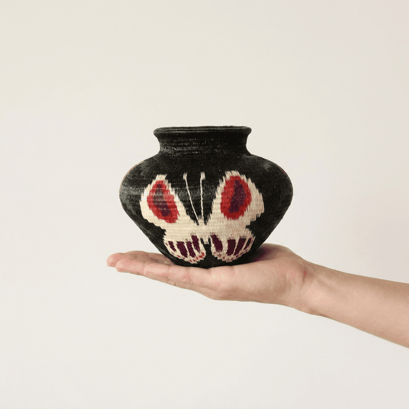 Black handwoven Wounaan butterfly basket with red eyespot wings held in hand showing miniature scale