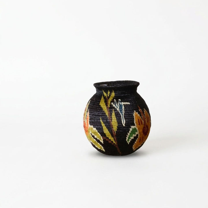 Handwoven Wounaan basket, orange lilies, chartreuse fronds and small blue-white winged figure on black weave