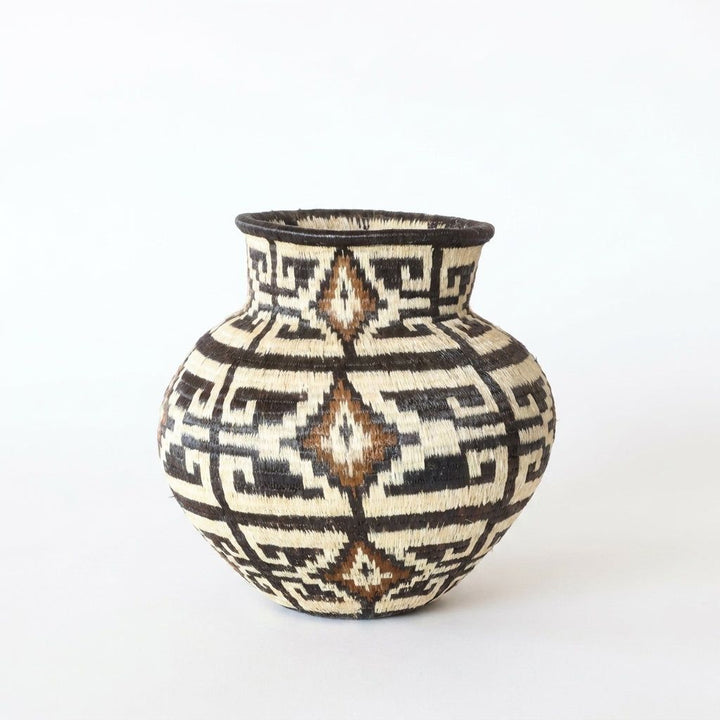 Close view of handwoven Wounaan basket showing labyrinth weave and cinnamon diamond column on ivory ground
