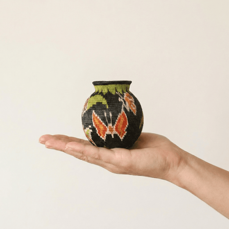 Night garden handwoven Wounaan basket held in hand showing miniature scale, floral and butterfly motif