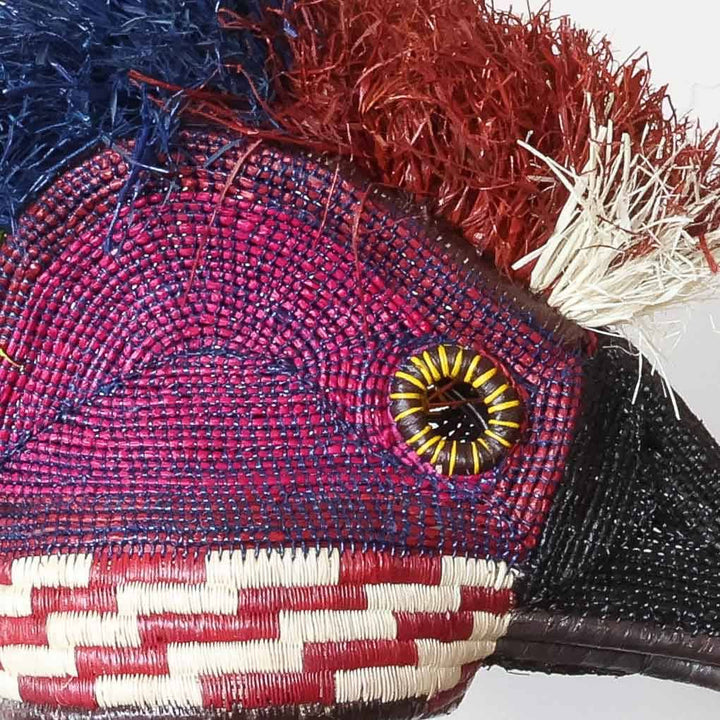 Close-up of intricate palm leaf weaving and natural dye work on ceremonial hummingbird mask craftsmanship