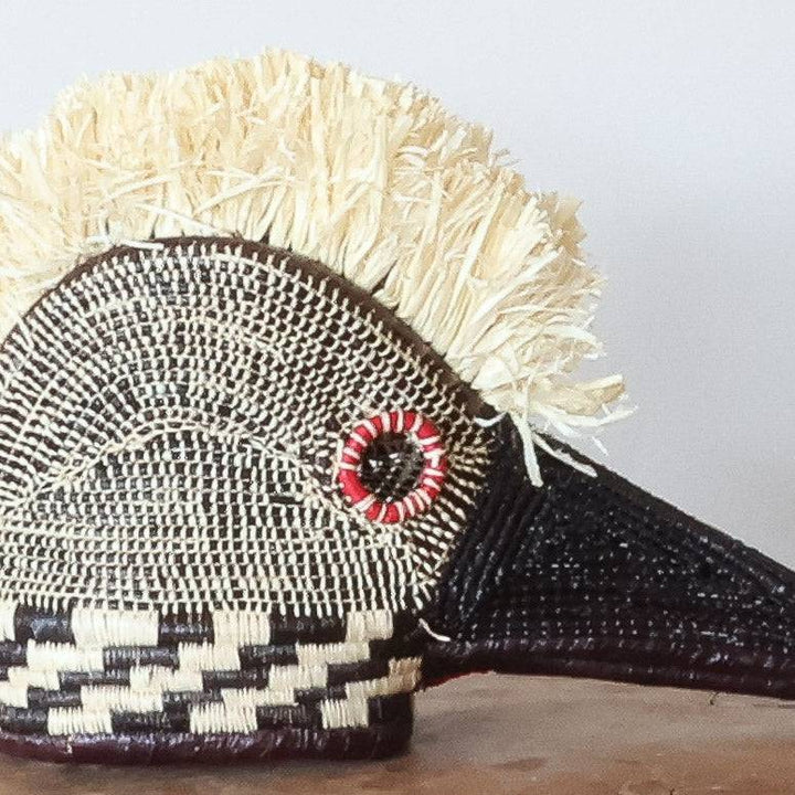 Close-up detail of palm leaf weaving and red eye pigment on miniature hummingbird spirit mask