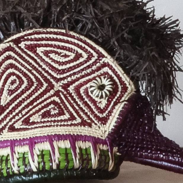 Close-up palm fiber weaving detail showing purple dye patterns on handmade Embera hummingbird mask