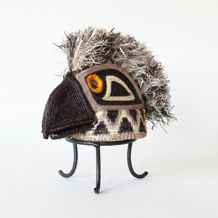 Handwoven Emberá eagle mask with a hooked beak, orange eye and straw crest, from Panama