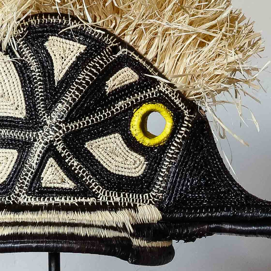 Detail of the woven geometric pattern and golden-yellow eye on an Emberá hummingbird mask