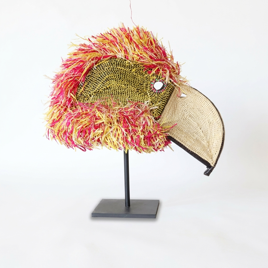 Handwoven Emberá parrot mask, golden beaded face, tan hooked beak and red-and-yellow raffia mane, from Panama