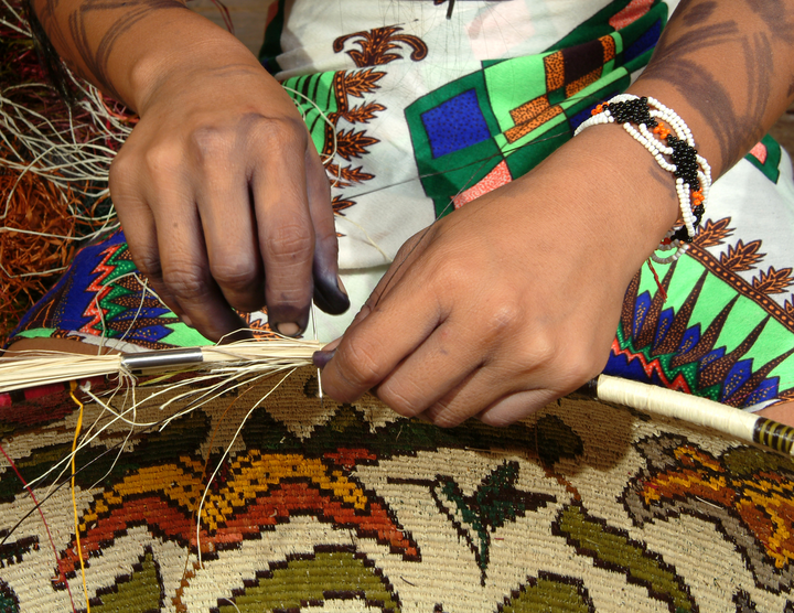 Loida Mejia stitching a hosig di basket, fiber and needle in hand