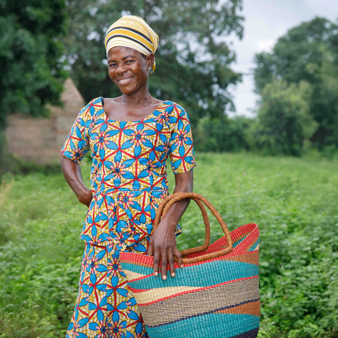 Bolga weaver standing in a field holding a finished handwoven basket, Bolgatanga, Upper East Region, Ghana