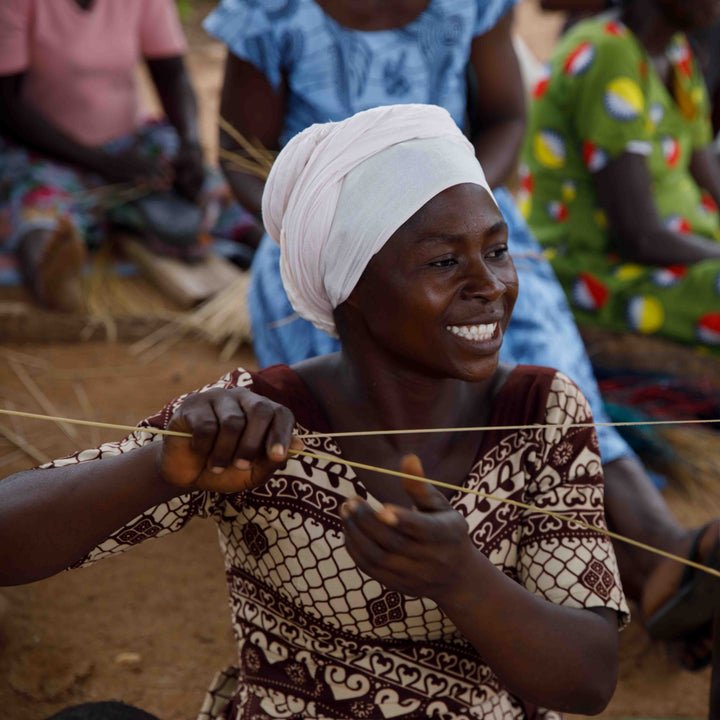 Bolga weaver smiling as she prepares elephant grass strands for weaving, Bolgatanga, Upper East Region, Ghana
