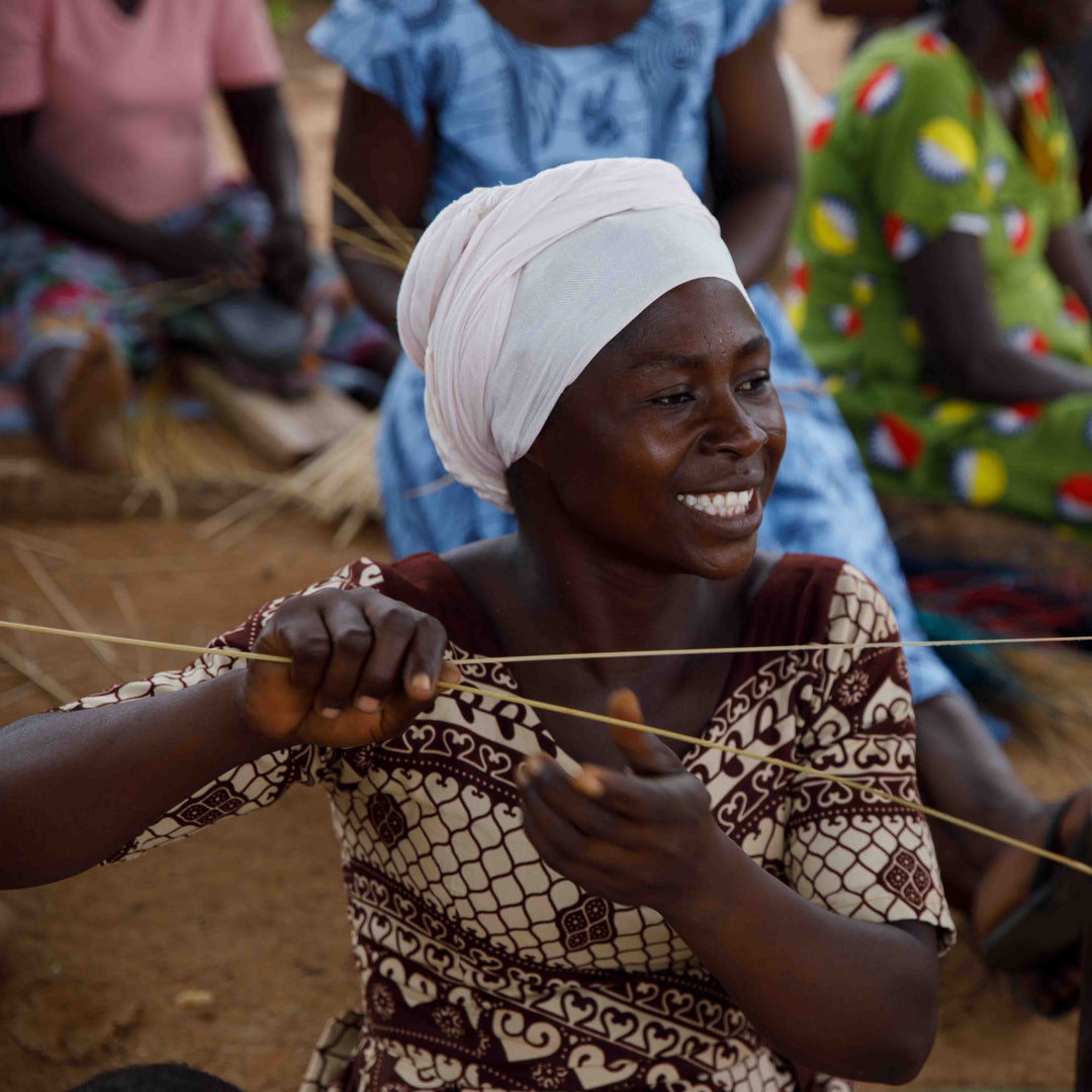 Bolga weaver smiling as she prepares elephant grass strands for weaving, Bolgatanga, Upper East Region, Ghana