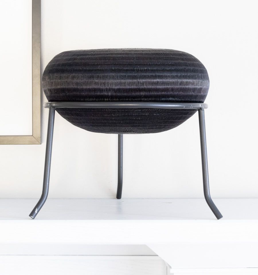 Black metal display stand showcasing handwoven decorative basket