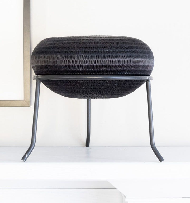 Black metal display stand showcasing handwoven decorative basket