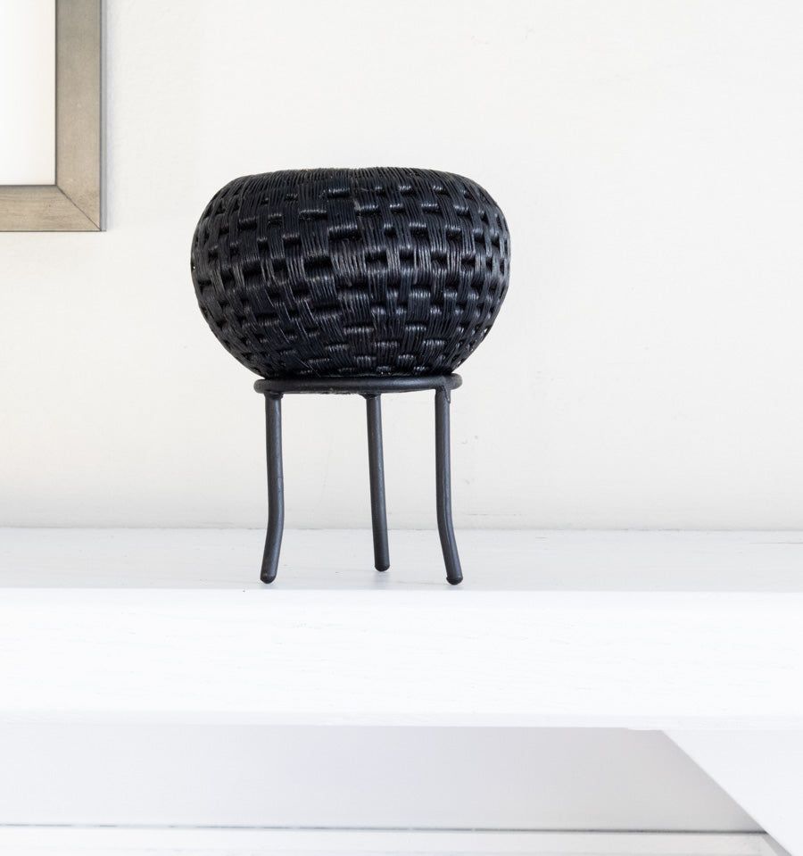 Black metal display stand showcasing handwoven decorative basket