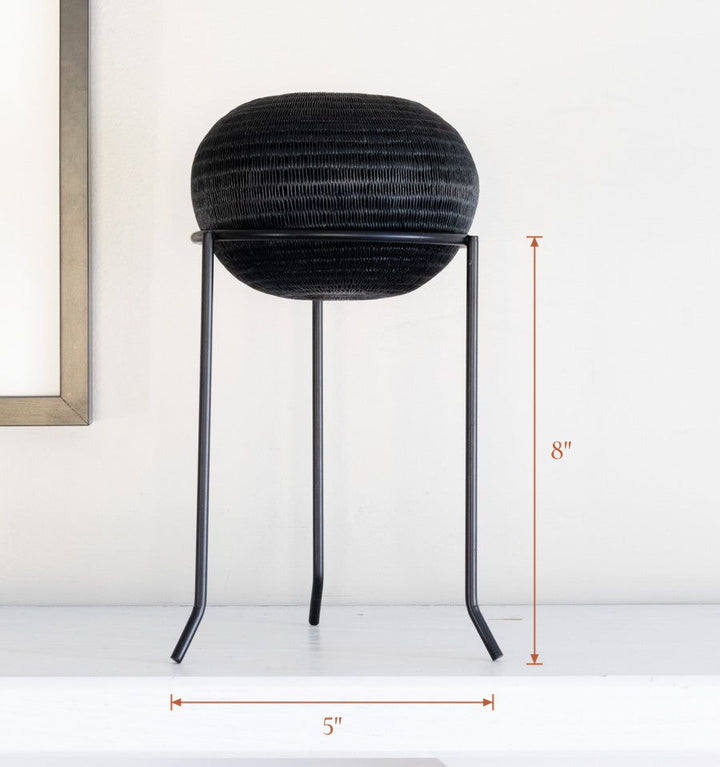 Black metal display stand showcasing handwoven decorative basket, stand 5 inches wide by 8 inches tall