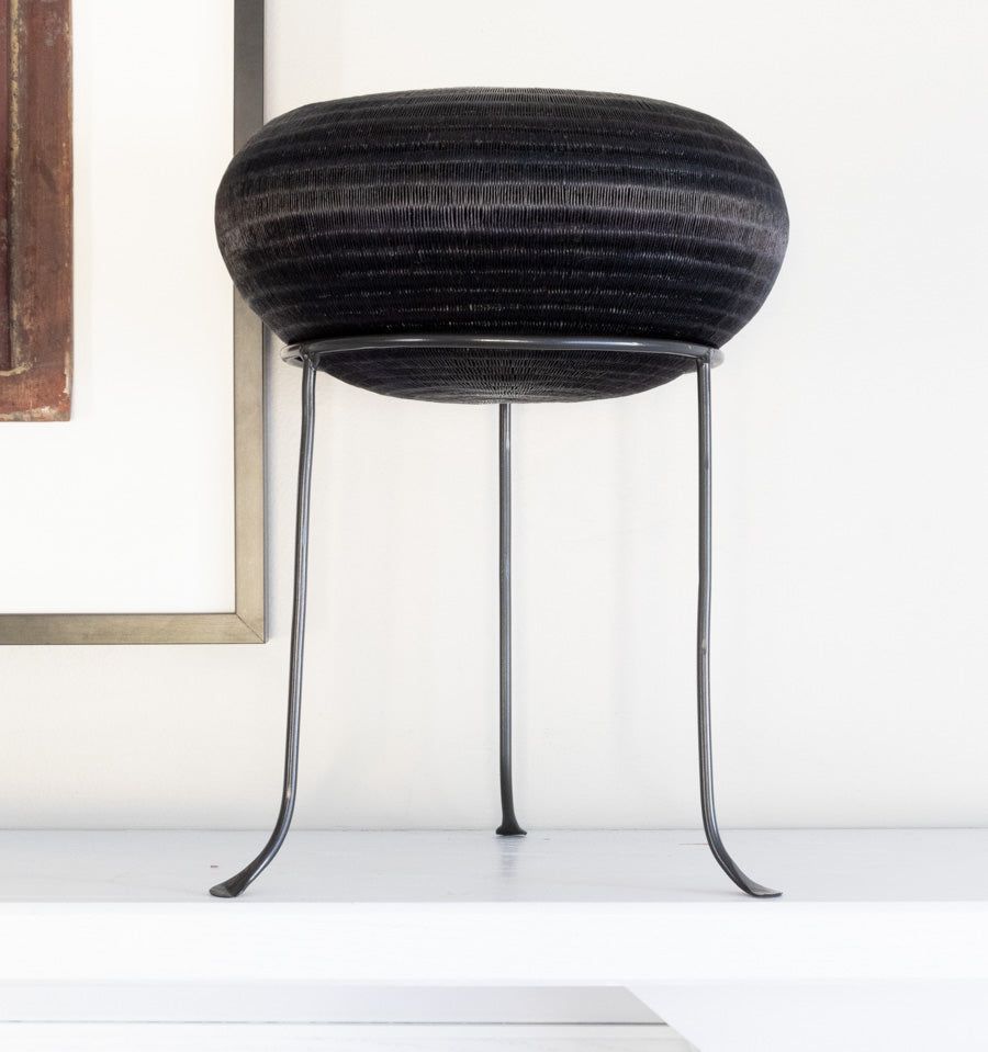 Black metal display stand showcasing handwoven decorative basket