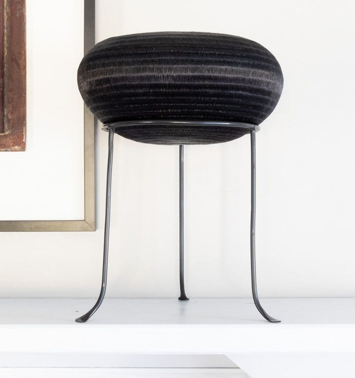 Black metal display stand showcasing handwoven decorative basket