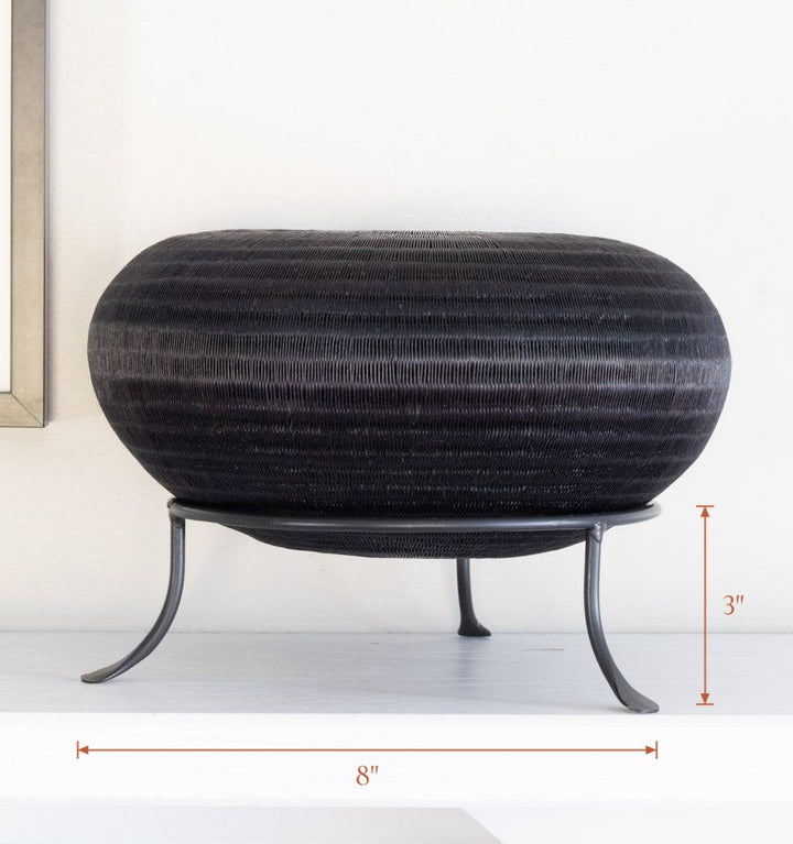 Black metal display stand showcasing handwoven decorative basket, stand 8 inches wide by 3 inches tall