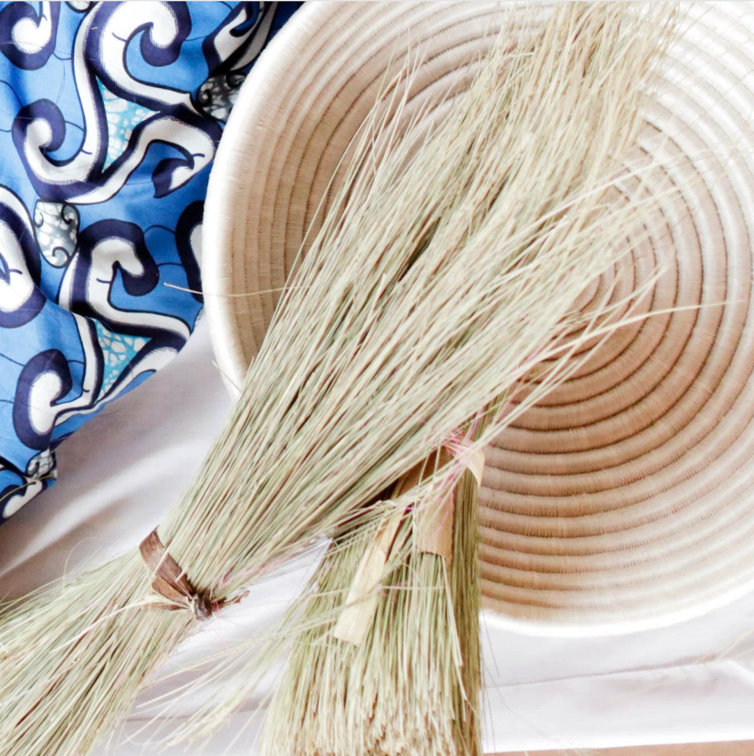 Bundles of wild sweetgrass resting on a coiled basket, the raw material of Rwandan weaving
